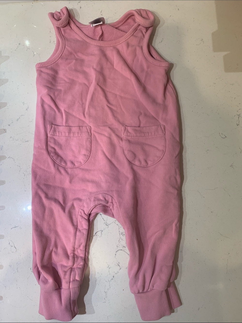 Hanna Andersson pink romper with snaps at legs and front pockets.